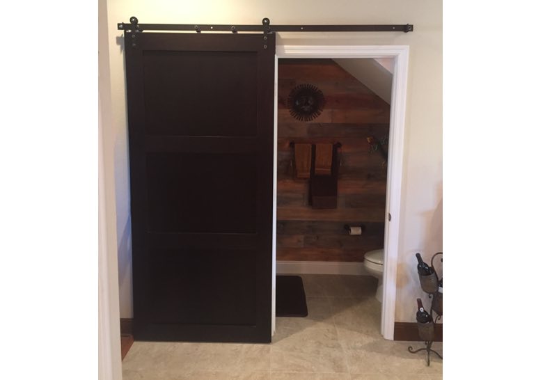 Dark brown barn door used as bathroom door 
